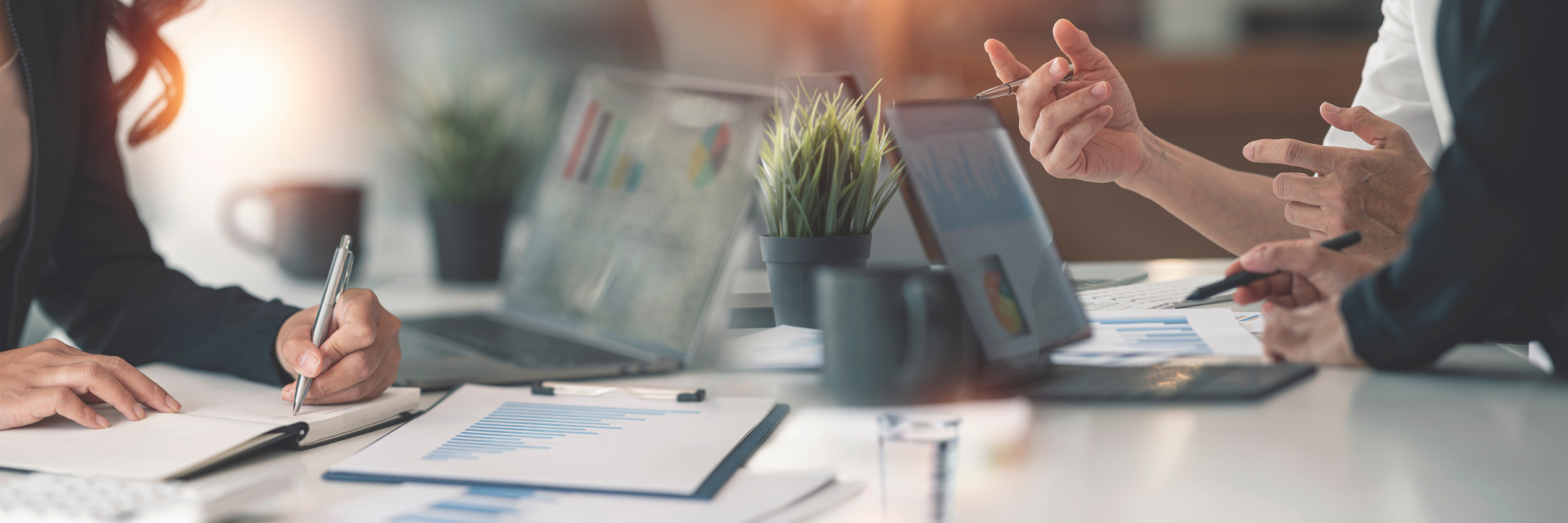 Symbolbild Büro Mehrere Personen besprechen Statistiken mit Laptop und Tablet an einem Bürotisch