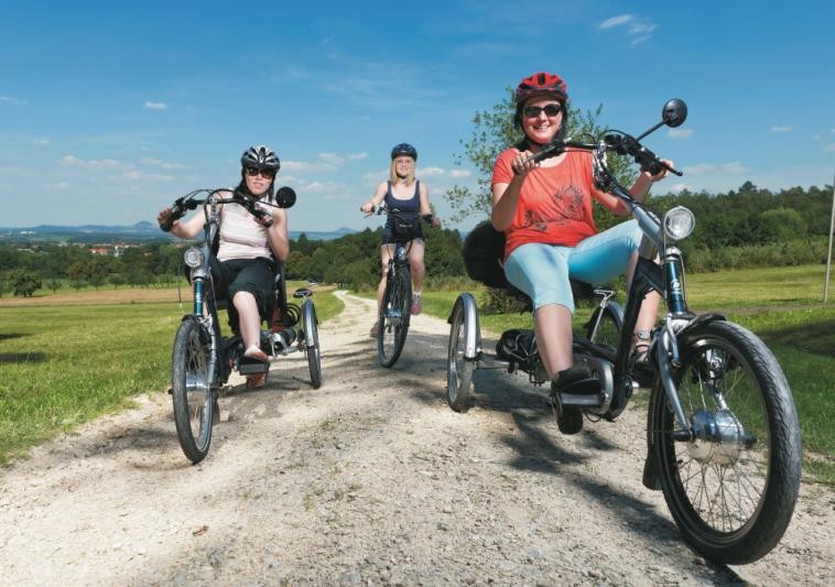 Drei Frauen auf den Drei- bzw. Fahrrädern fahrend auf dem Feldweg