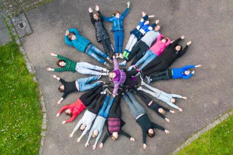 Gruppenbild von Jugendlichen mit und ohne Behinderung im Kreis liegend