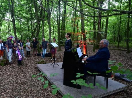 G. Buss am Klavier im Schlosswald mit Sängerin und Zuhörern