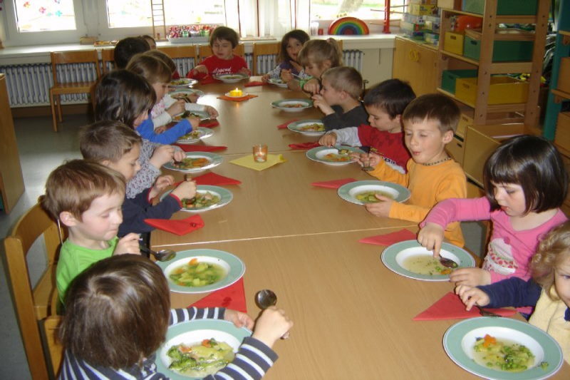 Kinder sitzen am Tisch und essen gemeinsam Gemüsesuppe 