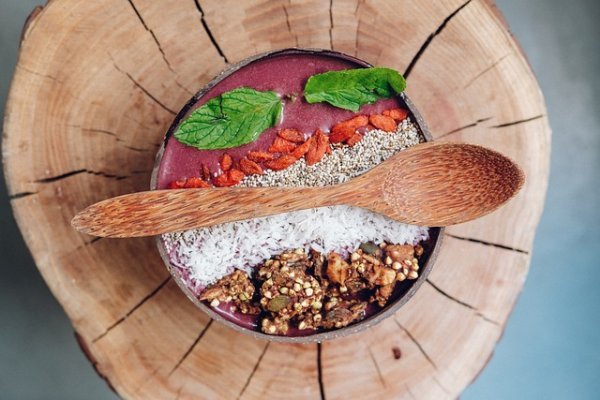 Bowl mit Reis und verschiedenen Zutaten in einer Schüssel auf Holzplatte